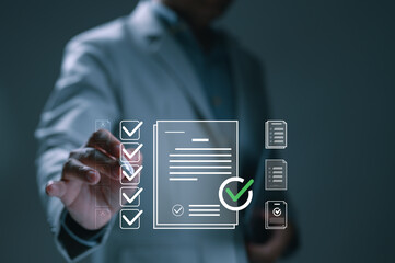 Businessman using virtual screen manages electronic documents. His hand ticks checkboxes on digital checklist, ensuring policy compliance. Concept represents business technology, automation, quality