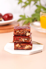 Delicious homemade date and nut bars stacked on plate - casual healthy snacks with refreshing drink