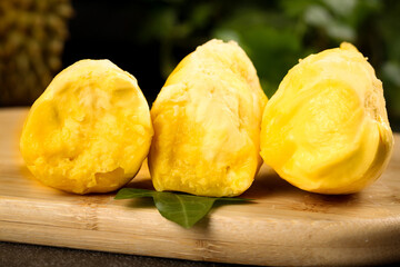 Fresh durian fruit cuts showing golden pulp on wooden board - healthy tropical exotic fruit still life