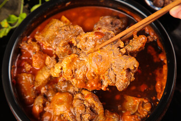 Spicy Korean Oxtail Soup with Bone-in Beef Tail Stew Being Served with Chopsticks in Traditional...