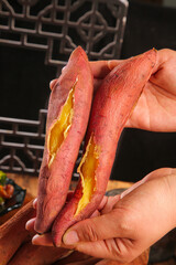 Fresh Roasted Sweet Potatoes with Golden Yellow Flesh Held in Hands