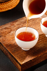 Traditional Chinese Puerh Tea Ceremony Pouring Dark Tea into White Cup on Wooden Tray