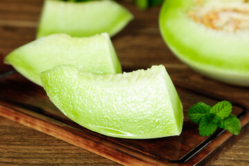 Fresh Honeydew Melon Slices on Wooden Board with Mint Leaves