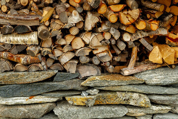 Wood is arranged in neat piles against a sturdy stone wall, highlighting warm hues and natural materials in a peaceful outdoor environment.