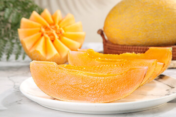 Fresh Golden Cantaloupe Melon Slices on Plate with Whole Fruit in Wicker Basket