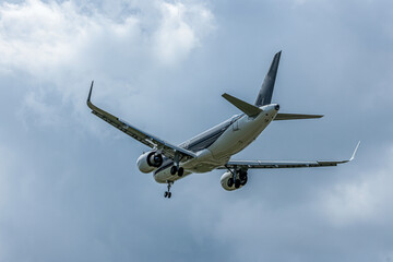 まぶしい夏の日差しの中で着陸するジェット機