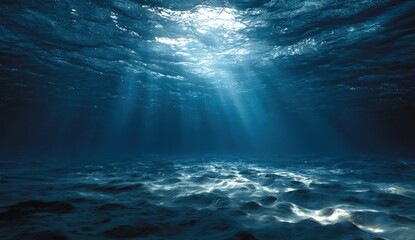 Sunlight streams through the dark blue ocean water creating ethereal beams illuminating the underwater seabed