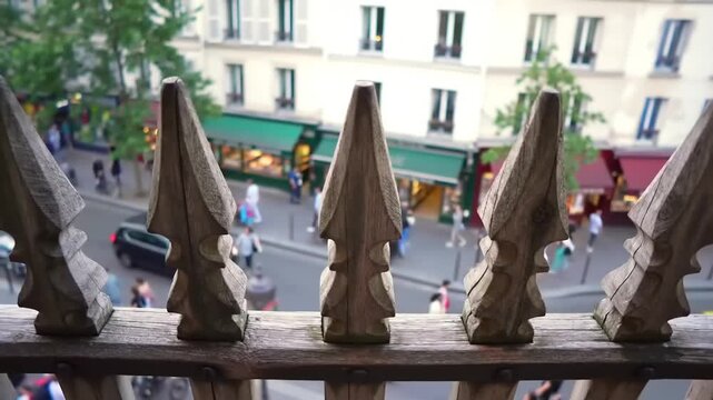 Ornate wooden fence posts frame a Parisian street scene.
