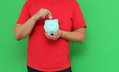 Dark-skinned Latino adult man shows off his piggy bank, happy and excited to save his savings for...