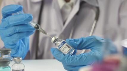 A healthcare worker wearing gloves draws a vaccine from a vial into a syringe at a clinic. The preparation is part of a community immunization effort aimed at improving public health.