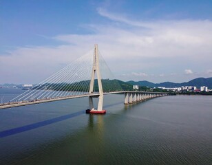Fototapeta premium Modern Cable-Stayed Bridge Spanning a Wide Body of Water with Distant Cityscape.