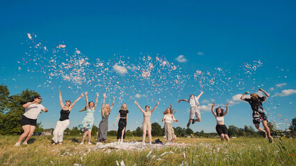 High school graduates express joy by tossing colorful confetti in the air while celebrating their newfound freedom in a sunny field