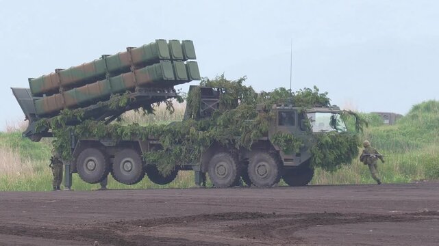 Defense truck raising missile launchers on a dusty field