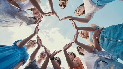 School friends coming together to form a star shape against a cloudy blue sky, representing unity,...