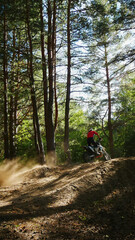 Fototapeta premium A enduro man jumps a dirt bike in a forest, soaring through the air