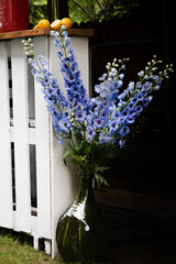 Blue delphinium flowers in a green glass vase, outdoor decoration