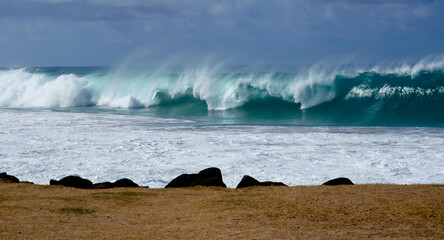 A powerful wave breaks along the southern shore of Kauai