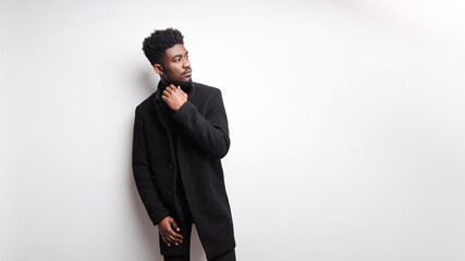 Serious young guy in black clothes looking away at white background