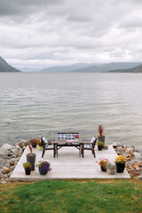 Wooden furniture of table and two chairs standing on lake shore