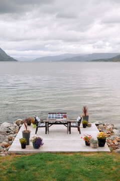 Wooden furniture of table and two chairs standing on lake shore