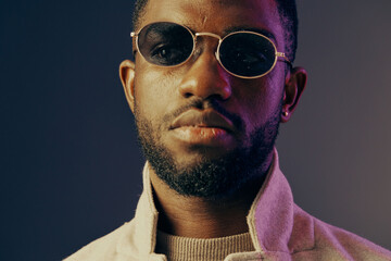Confident young man with stylish sunglasses and a fashionable coat, showcasing warmth and style...