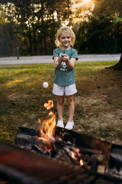 Child roasting marshmallow over campfire at campground
