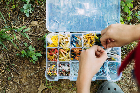 Close up of hands choosing fishing bait from tackle box