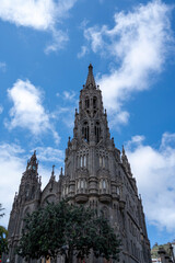 Fototapeta premium A tall building with a steeple and a clock tower. The sky is blue and there are clouds in the background