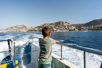 Young boy admiring the coastal cityscape of roses, girona, from a boat, creating lasting summer...