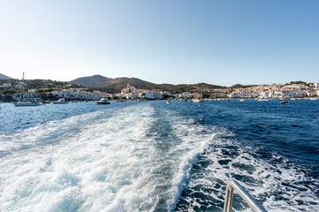 White foam trail following boat sailing away from cadaques, a picturesque town on the costa brava in catalonia