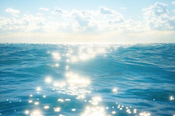Obraz premium Sunlight sparkling on clear blue ocean waves under a bright cloudy sky creating a peaceful and serene atmosphere