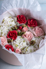 Home-made zephyr floristry arrangement featuring delicate pink, white, and red floral designs nestled in a soft tissue-lined container, showcasing artistry and creativity in dessert presentation