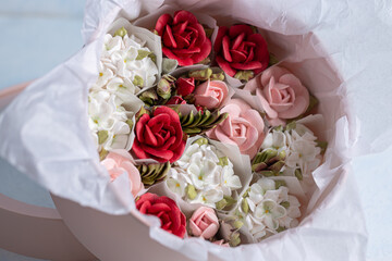 Home-made zephyr floristry arrangement featuring delicate pastel flowers and vibrant red roses, beautifully presented in a soft pink container with elegant wrapping