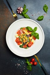 Appetizing Caesar salad with salmon and croutons. In a white round plate, on a stone background. Close-up. Seafood salad.