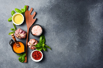 Spices: Oil, salt, fresh garlic and basil, peppercorns in ceramic bowls. Top view.