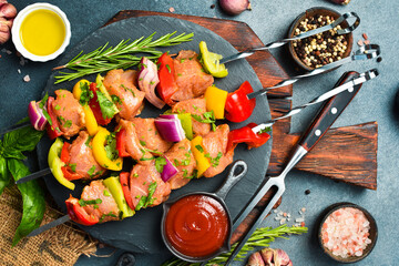 Metal skewers with chicken and vegetables. On a black slate plate. Top view. Barbecue concept.