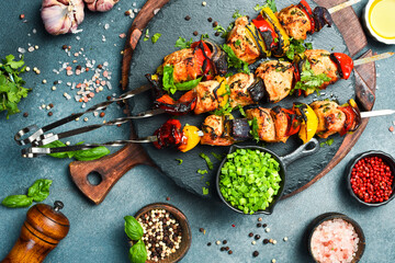 Shish kebab from chicken breast, and grilled vegetables on metal skewers. Top view. On a black background. © Yaruniv-Studio