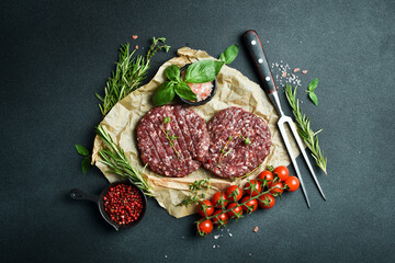 Raw veal burger cutlet with spices and herbs. Ready to cook. On a dark stone background. Top view.