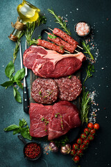 Barbecue party. T-bone steak, ribeye steak, kebab and burger patty. On a black stone background. Top view.