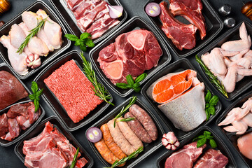 Black plastic packaging trays from supermarket with different types of fresh raw meat cuts, fresh beefbeef steaks, fish and variety meats in boxes from above