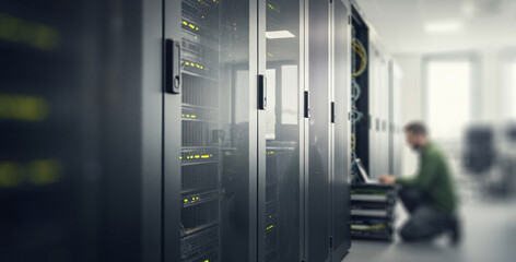 Server room with racks and a person working on a laptop.