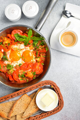 Shakshuka eggs in a pan with toast on a black concrete background. Poached eggs in a spicy tomato pepper sauce. Traditional Jewish breakfast. Healthy meal.