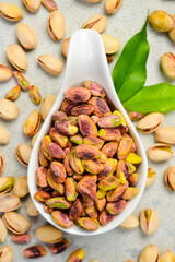 White ceramic bowl with peeled pistachio kernels. Nuts ready to eat. Top view. On a white background.