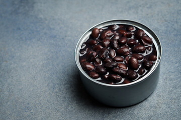 Canned beans in a metal can. Food for tourism or recreation. On a gray concrete background.