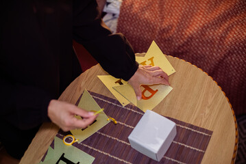 Hands carefully assemble a shimmering golden 'Happy Birthday' banner on a wooden table, preparing...
