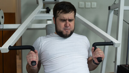 Man working out on a chest press machine, focused and straining during strength training at the gym.