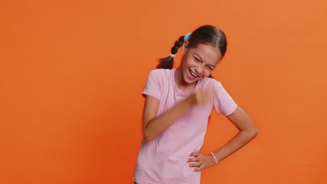 Happy preteen child girl kid laughing out loud after hearing ridiculous anecdote reaction on funny joke feeling carefree amused. Positive people. Teenager children isolated on studio orange background