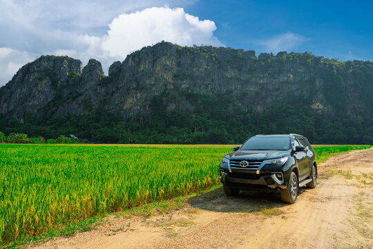 Nan, Thailand - Oct 20, 2023 A Toyota 4x4 off-road Fortuner drives on a beautiful mountain road. Rear view of the high mountains and undulating road. Nan Province, Thailand.