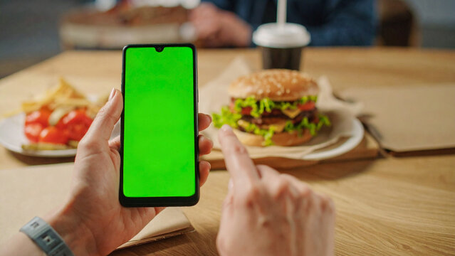 Person Using Smartphone with Green Screen While Eating Fast Food