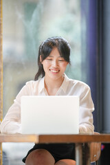 A woman is sitting at a table with a laptop in front of her. She is smiling and she is enjoying herself